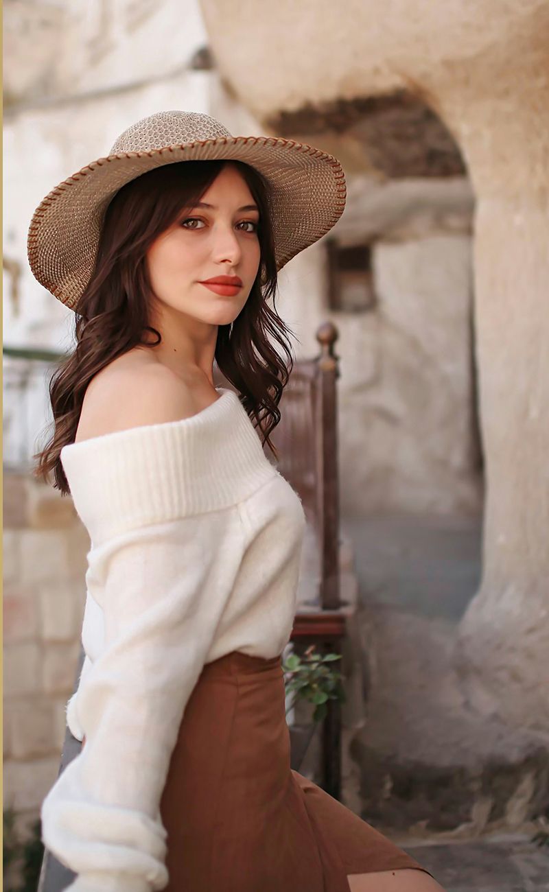 Woman in hat with curled hair and makeup.
