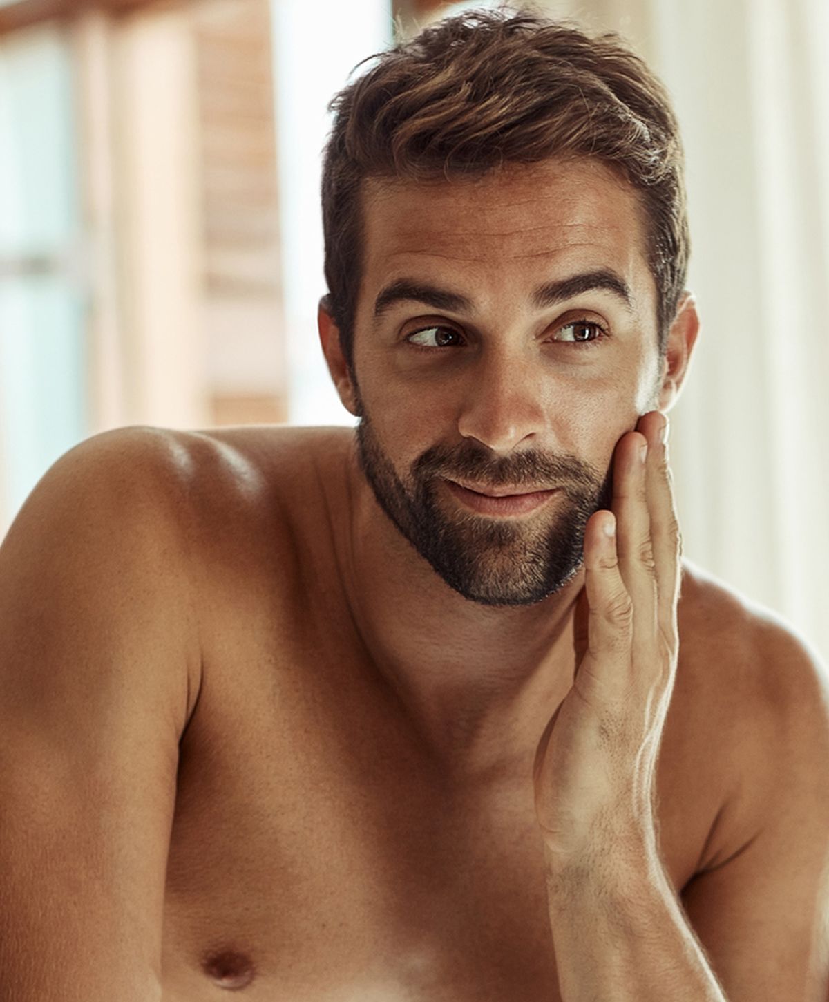 Man with beard touching his face thoughtfully.