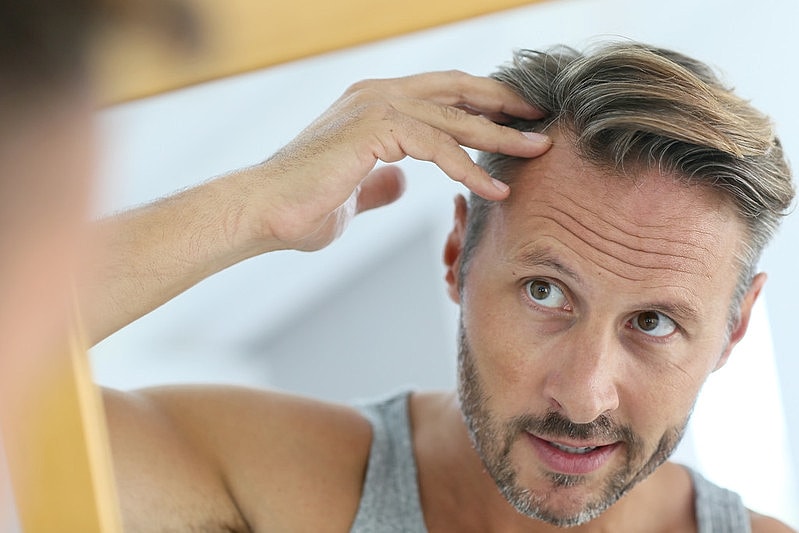 Man examining his hair in the mirror.