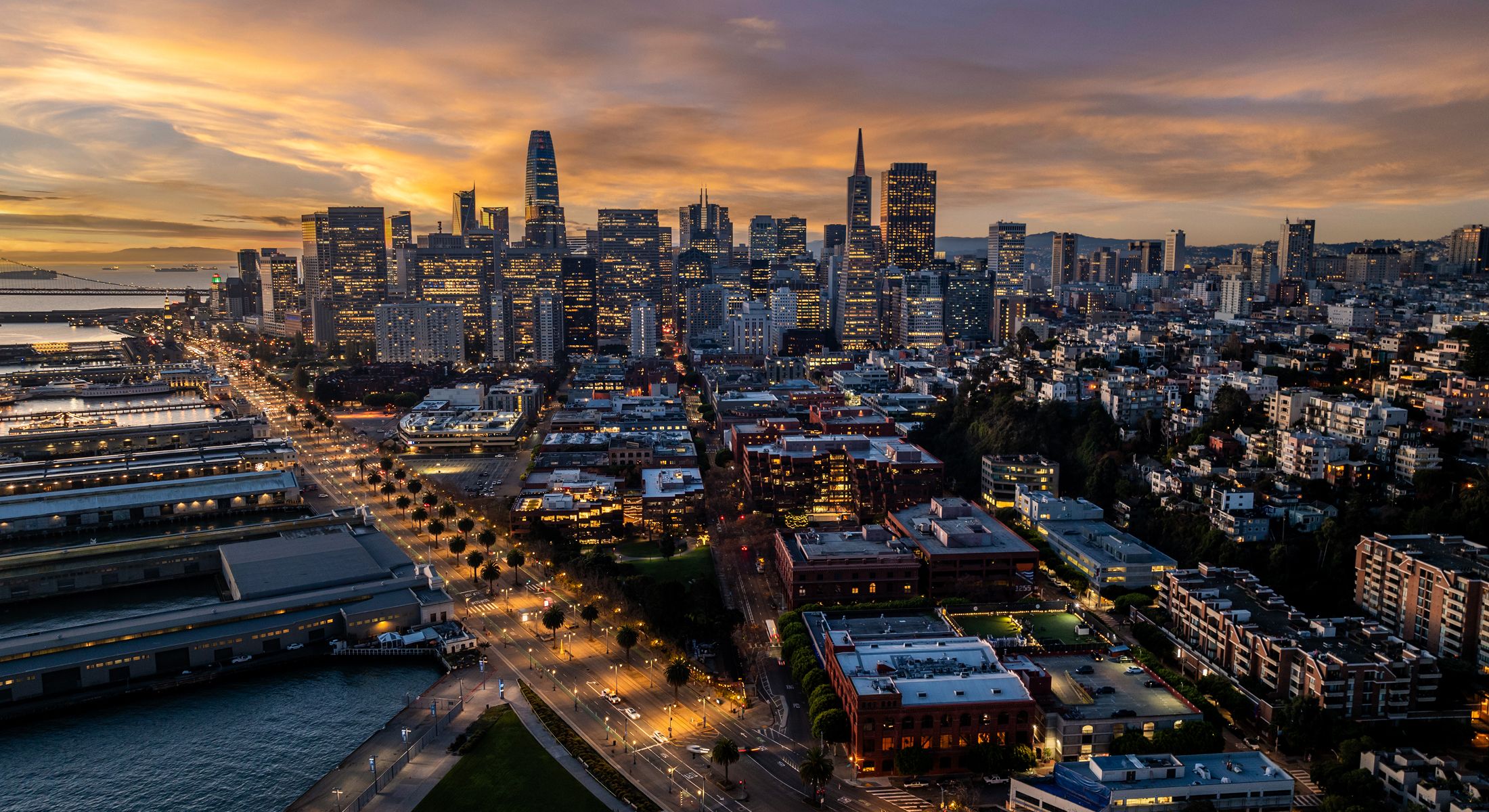 San Francisco skyline at sunset with city lights.
