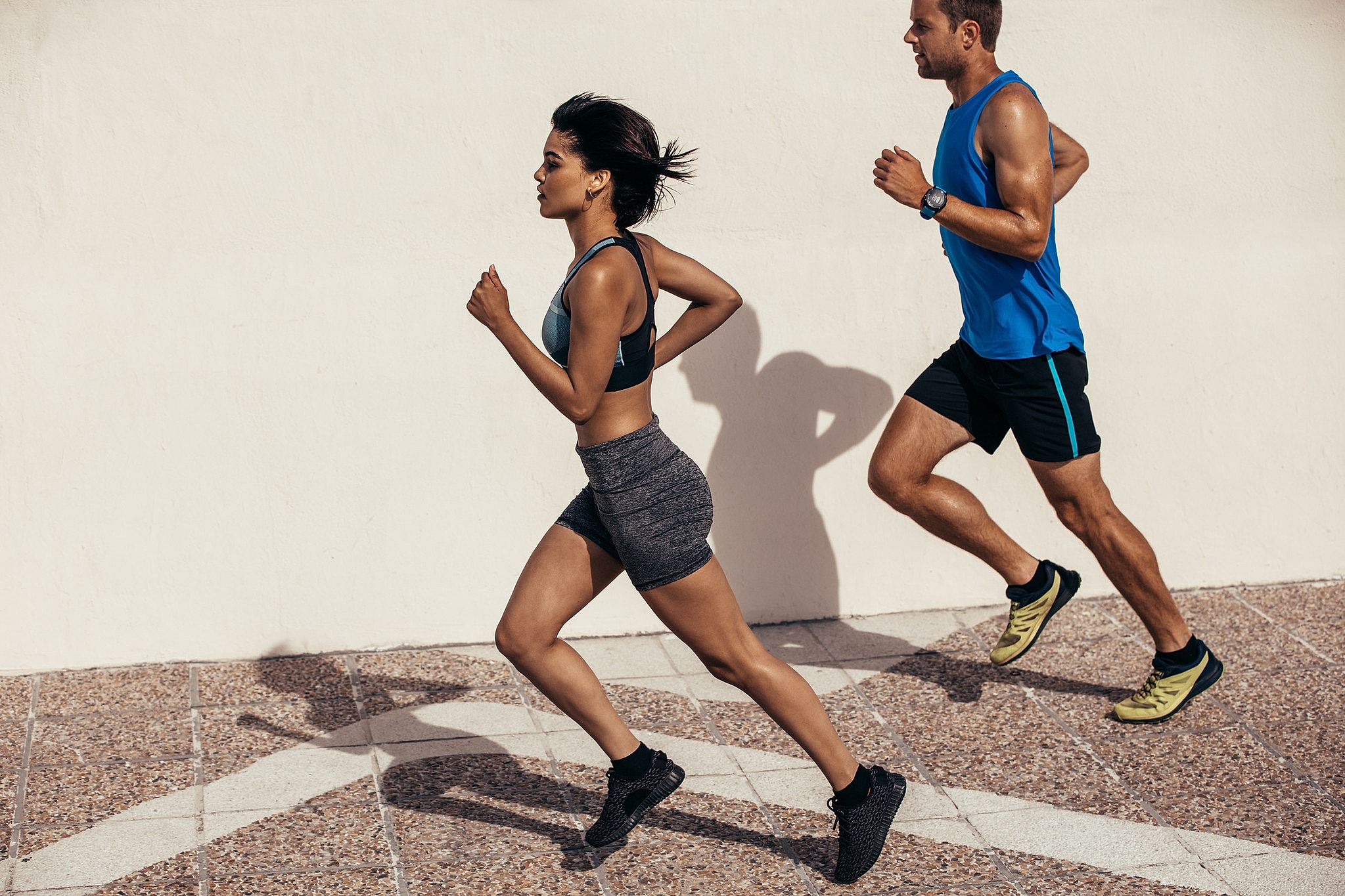 Athletic man and woman running outdoors.